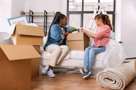 two women packing a box in a living room