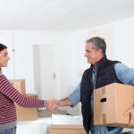 Young woman shaking hands with a mover to help illustrate do you tip home movers